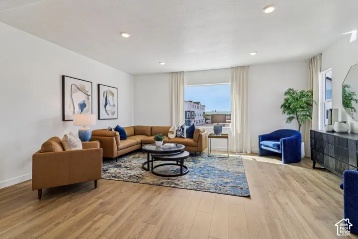 Recessed ceiling lighting, white walls, wood-finish flooring, a large window, and white window treatments