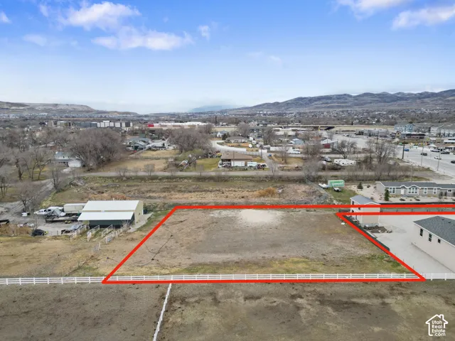 Expansive undeveloped lot with perimeter fencing and distant mountain ranges