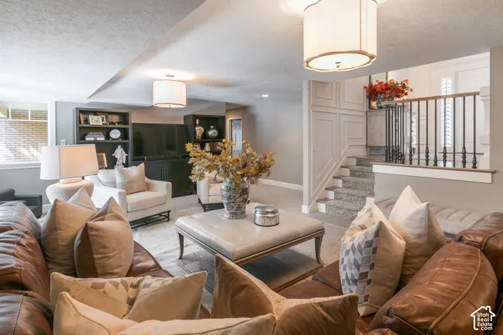 Built-in shelving, overhead lighting fixtures, staircase with wrought iron balusters, wainscoting, and carpeted stairs