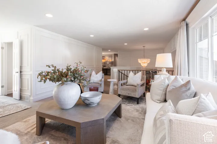 Recessed lighting illuminates panel detailing, complemented by a decorative chandelier and large windows