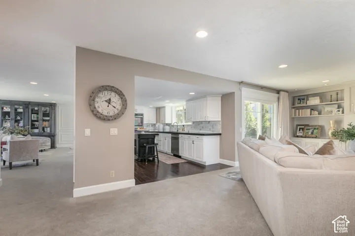 Recessed lighting, built-in shelving, white cabinetry, dark countertops, and dark wood-finish flooring
