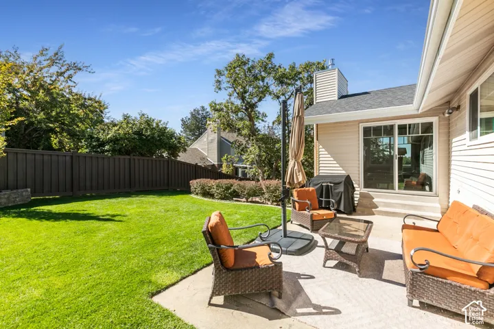 Expansive lawn with perimeter fencing, concrete patio, and mature landscaping