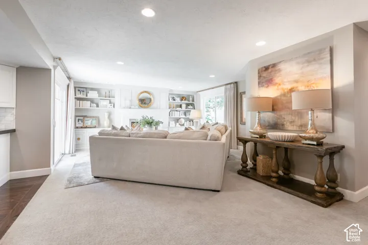 Recessed lighting, built-in shelving, white cabinetry, wood-finish flooring, and light-colored carpeting