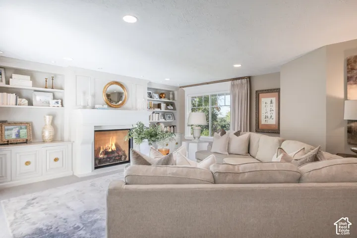 Fireplace with a white mantel, built-in shelving, recessed lighting, and a large window with drapes