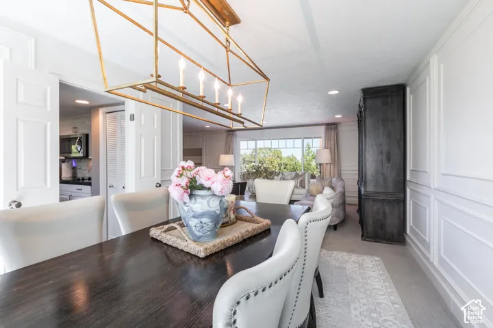 Formal dining area featuring a dark wood-finish table, a gold-finish linear chandelier, and decorative wall paneling