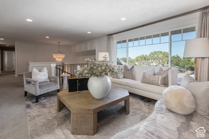 Sophisticated primary suite featuring expansive windows with natural light, recessed ceiling lights, neutral wood-finish flooring, plush seating areas with coordinating upholstered chairs, and a wood-frame crib as a permanent architectural element