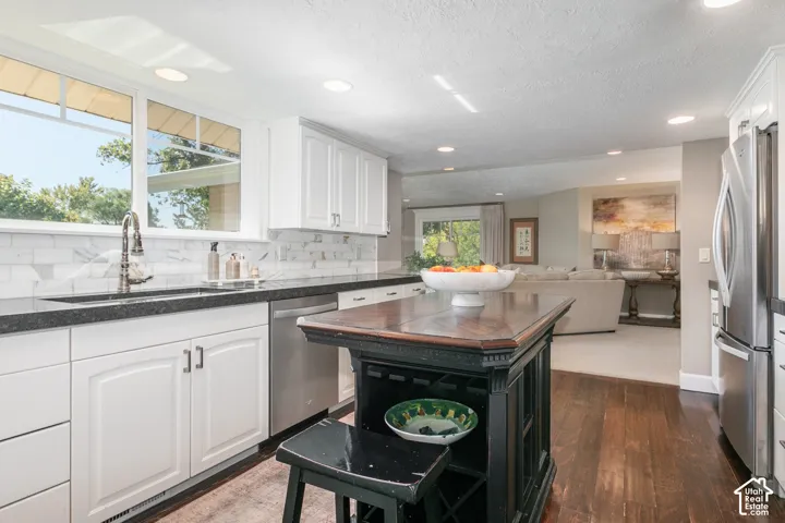 White cabinetry with brushed nickel hardware, granite countertops, stainless steel appliances, wood-finish flooring, and recessed lighting