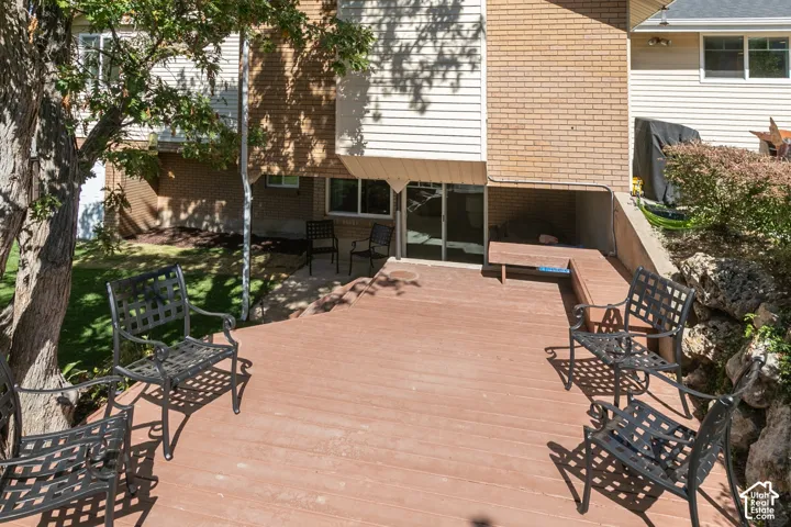 Expansive composite deck with wood-finish flooring, offering multiple seating areas shaded by mature landscaping