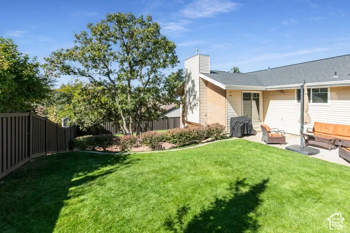 Expansive backyard featuring a manicured lawn, established perimeter fencing, and mature trees