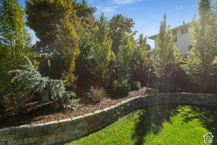 Manicured lawn with a stone retaining wall and lush landscaping