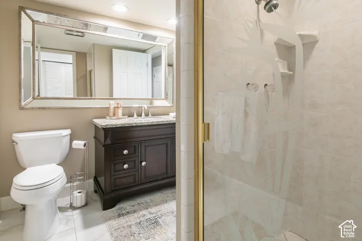Dark wood vanity with a light-toned countertop, framed mirror, and tiled shower with etched glass