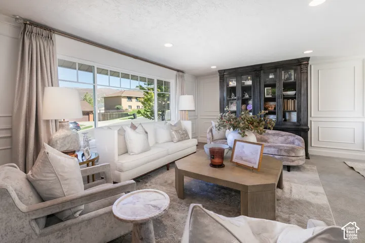 Expansive window, recessed lighting, decorative wall paneling, built-in display cabinetry, and wood-finish coffee table