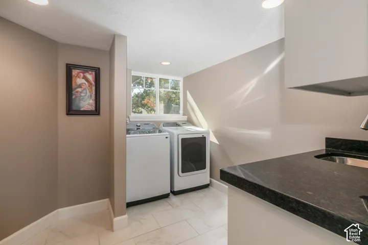 Laundry area featuring a window, tile flooring, recessed lighting, and a utility sink with a dark countertop