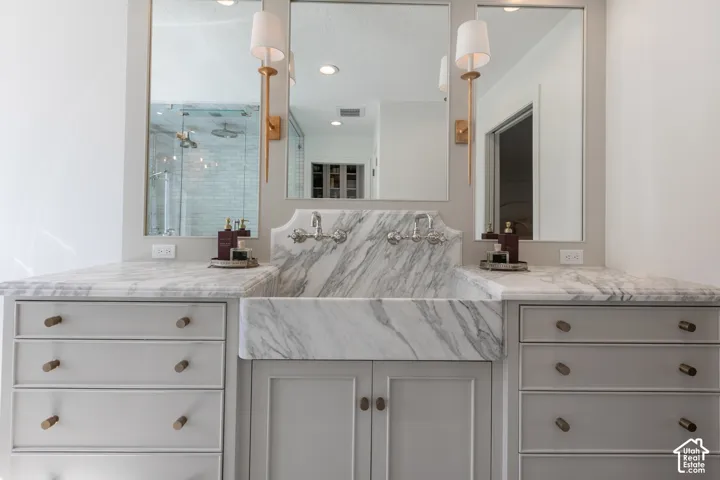 Integrated farmhouse sink with wall-mounted faucets, dual mirrors with sconce lighting, and built-in cabinetry with drawer storage