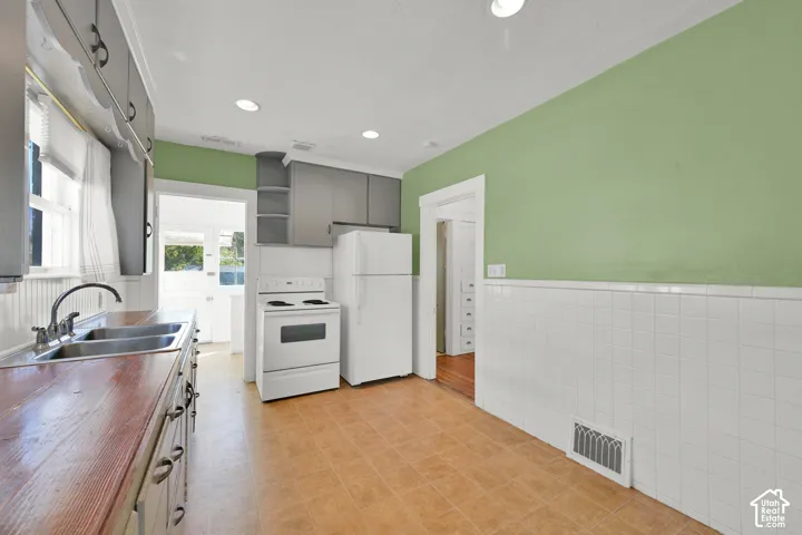 Wood-finish countertops, dual basin stainless steel sink, tile wainscoting, and recessed lighting