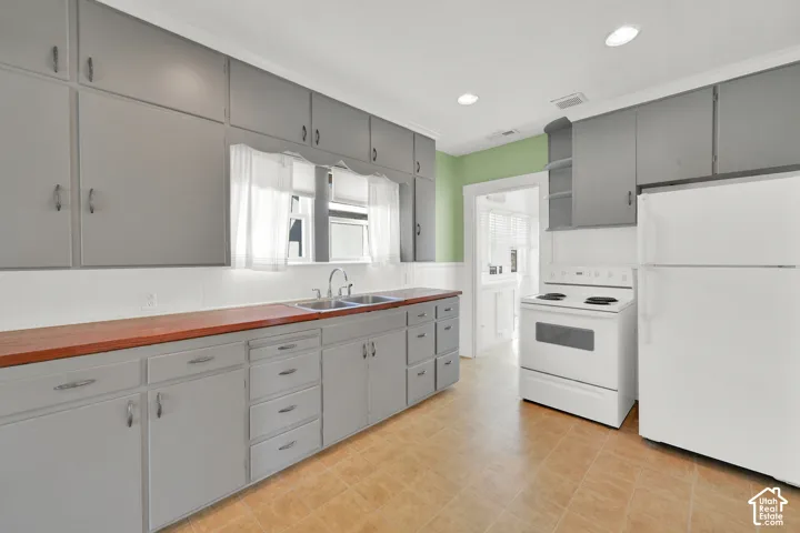 Kitchen featuring extensive gray cabinetry, durable wood-finish countertops, tile flooring, and a double basin sink