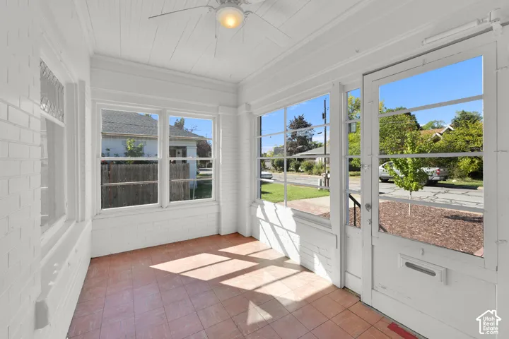 Enclosed porch featuring a wood-panel ceiling, tiled flooring, multiple windows, and a ceiling fan with light fixture