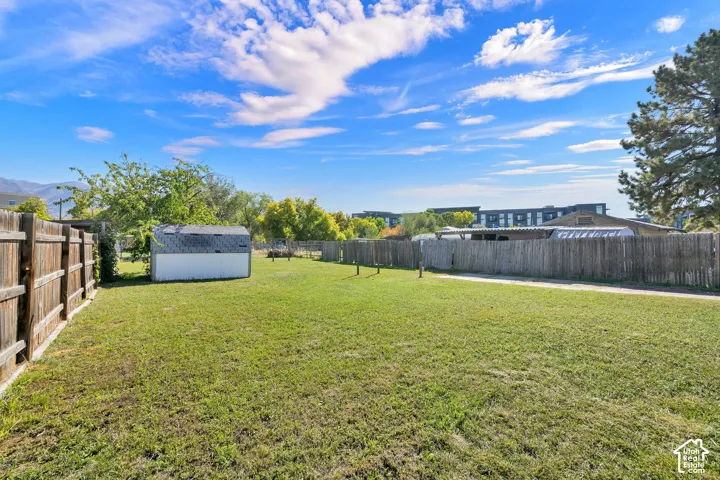 Expansive grassy yard with wood fencing and a storage shed