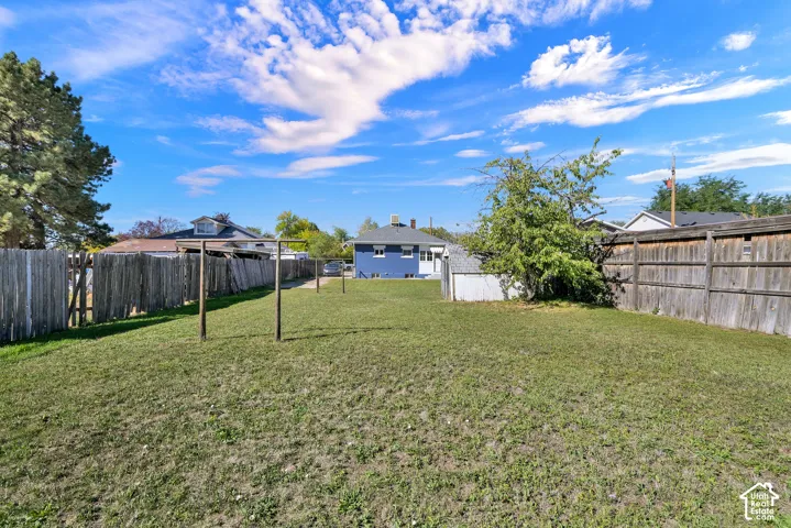 Expansive backyard featuring a manicured lawn, established trees, and a wooden privacy fence