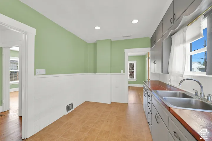 Kitchen area featuring dual stainless steel sinks, wood-finish countertops, grey cabinetry, and recessed lighting