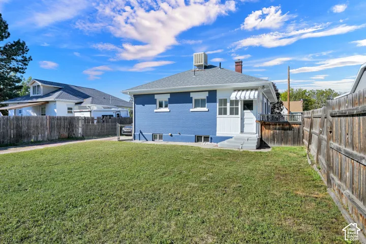 Charming blue cottage with a spacious, level lawn bordered by wooden fencing