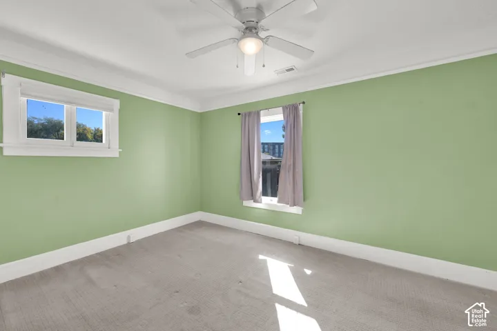 Bright interior featuring carpet flooring, crisp white trim, and a ceiling fan with integrated lighting