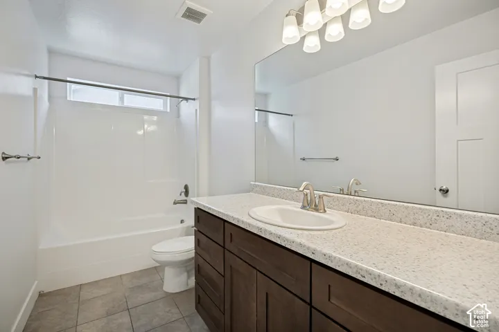 White tub and shower combination with an upper transom window, vanity with wood-finish cabinetry, light-colored countertop, and a large wall-mounted mirror