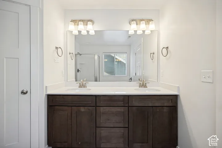 Double vanity with dual undermount sinks, stone-finish countertop, dark wood-finish cabinetry, and brushed nickel fixtures