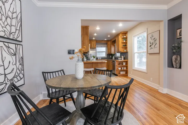 Hardwood flooring, crown molding, built-in kitchen cabinetry, recessed lighting, and a built-in wall niche