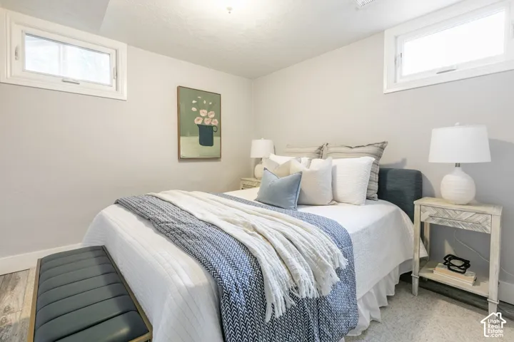Windowed bedroom with light gray walls, white trim, and wood-finish flooring