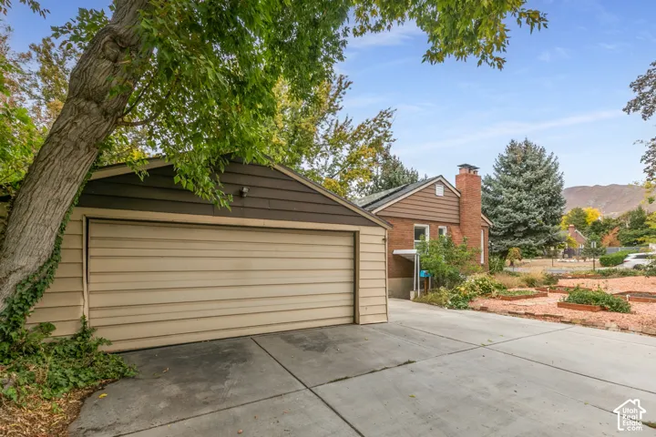 Attached two-car garage with horizontal siding, concrete driveway, and established landscaping
