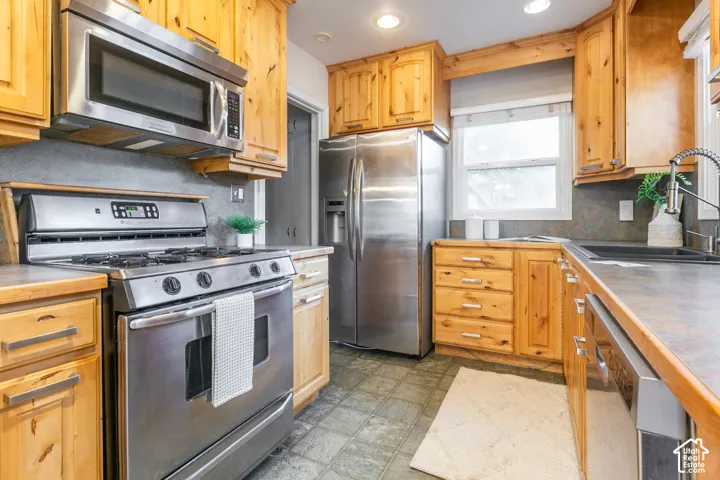 Full kitchen featuring stainless steel appliances, wood cabinetry, and a window above the sink