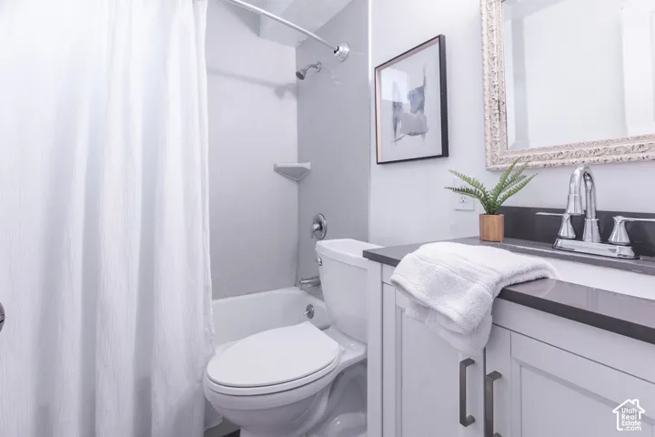Bathroom with white vanity, dark countertop, chrome faucet, and integrated sink