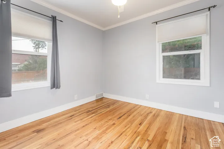 Wood-finish flooring with white trim, light gray walls, and white window frames