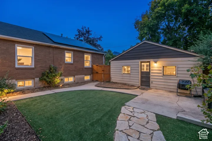 Brick exterior with solar panels, artificial turf lawn, flagstone pathway, and detached auxiliary building