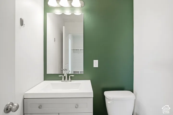 Vanity with integrated sink, chrome faucet, wall-mounted mirror, and overhead lighting