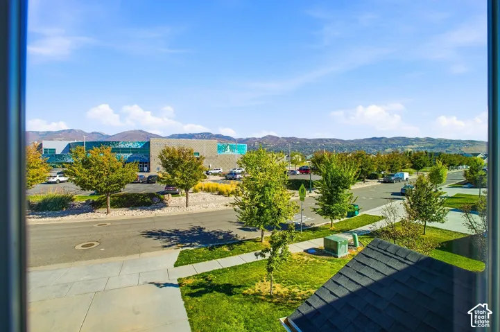 Clear blue sky with scattered clouds, a paved street, and mature trees lining the road