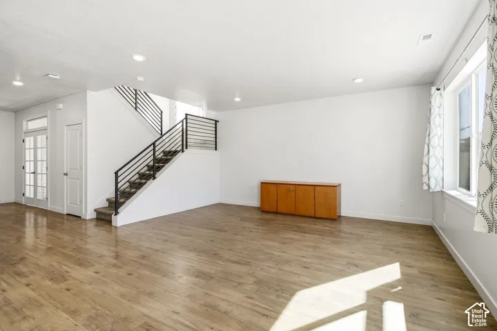 Wood-finish flooring throughout, modern staircase with black metal railings, recessed lighting, and white walls