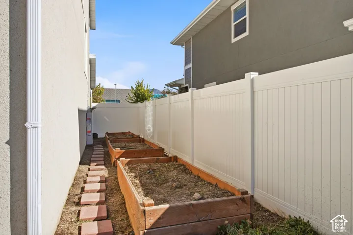 White privacy fencing, raised garden beds, and a paver pathway