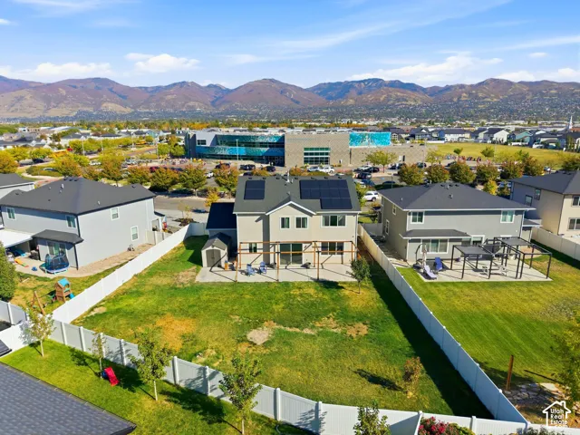 Expansive yard with privacy fencing, mountain backdrop, paved patio, and upper-level balcony