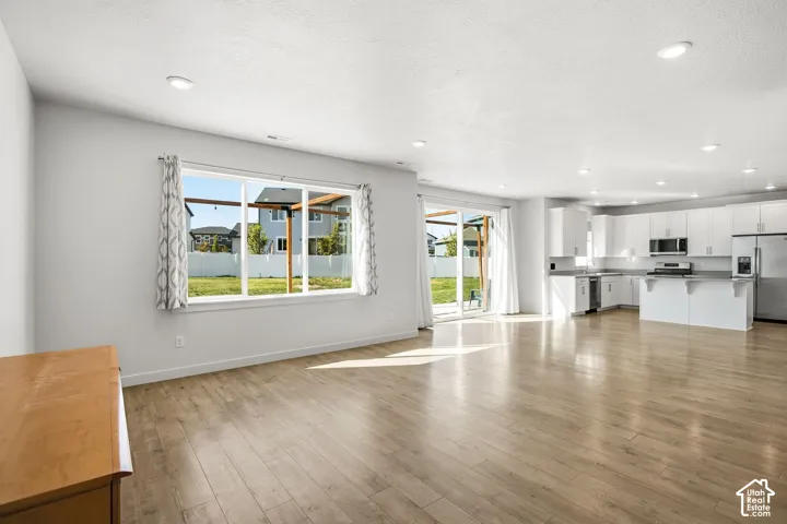 Recessed lighting, wood-finish flooring, white cabinetry, stainless steel appliances, and sliding glass doors