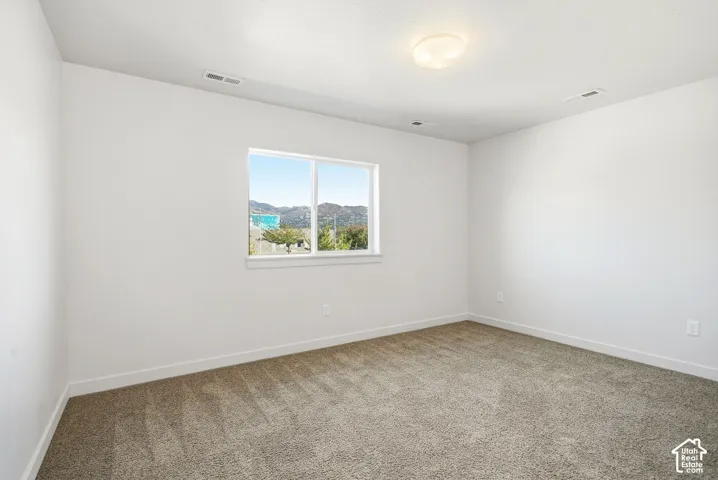 White walls, neutral carpeting, and a single window with white trim