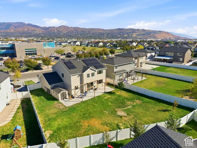 Rear exterior with an expansive fenced yard, extended concrete patio, wood pergola, and solar panels