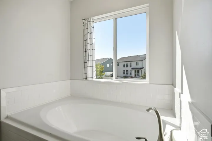 Soaking tub with a brushed nickel faucet, subway tile surround, and an expansive window