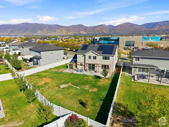 Expansive backyard with a manicured lawn, white privacy fencing, and a built-in pergola