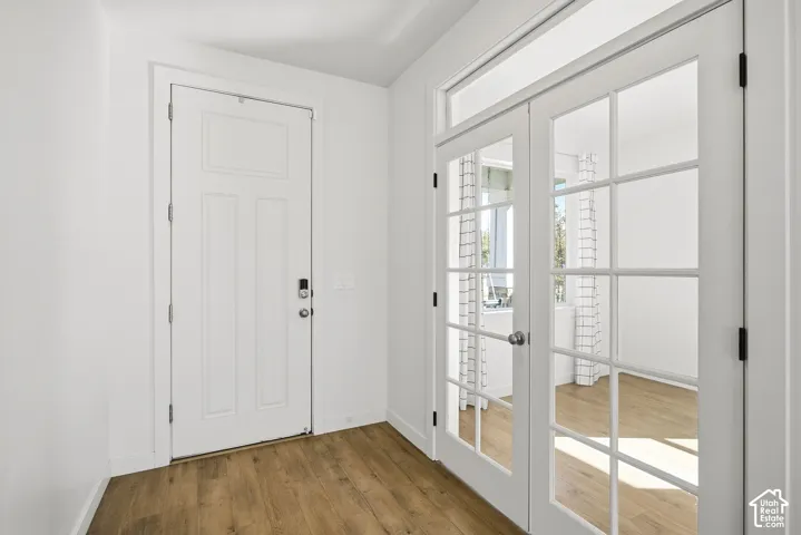 Entryway featuring wood-finish flooring, a white paneled door with smart lock, and French doors with transom windows