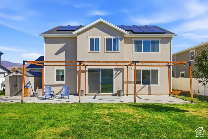 Stucco exterior with a dark shingle roof featuring solar panels