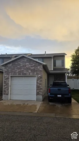 Brick and siding exterior, attached garage, concrete driveway, and white privacy fencing