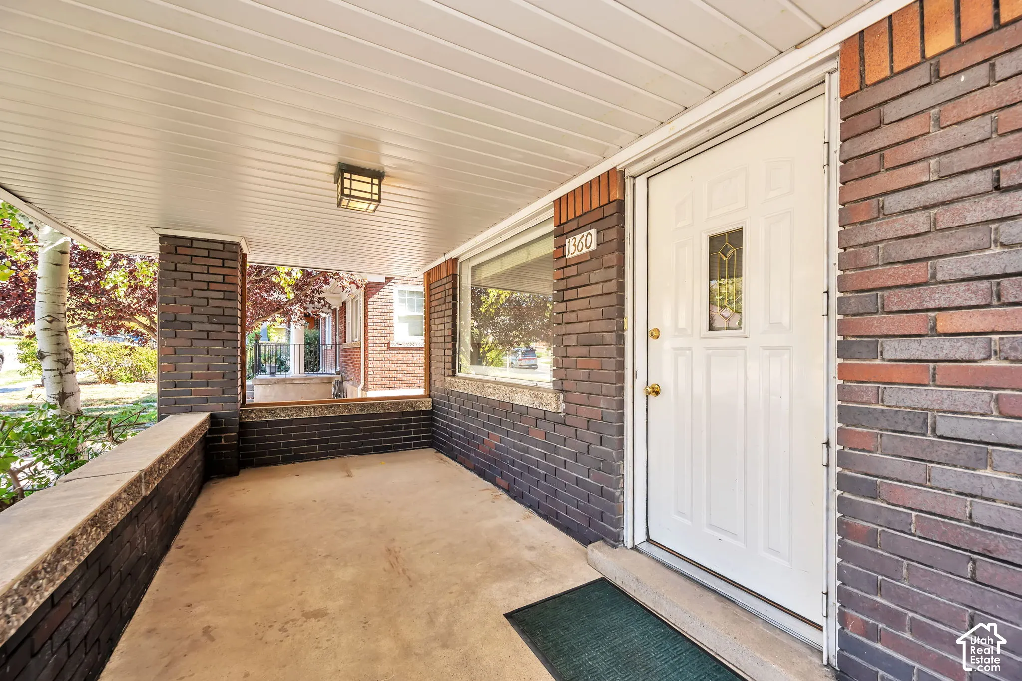 Large covered porch, concrete flooring, entry door with an ornamental glass insert