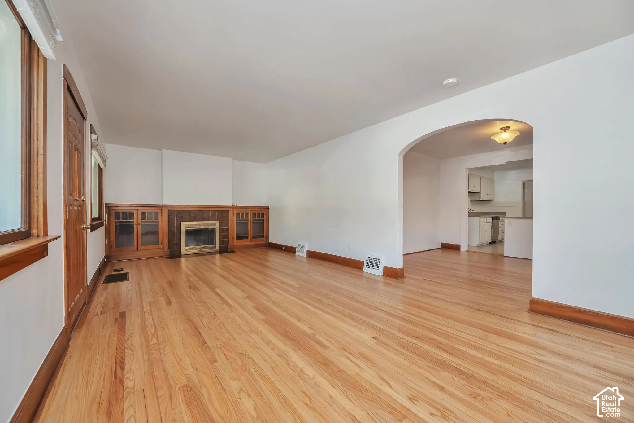 Hardwood flooring, fireplace with wood surround and built-in cabinetry, with arched entryway to dining room.